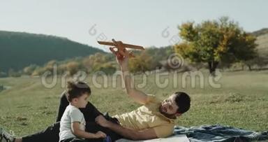 在<strong>大</strong>自然的中间，儿子和他的父亲一起玩<strong>大飞机</strong>，他们躺在草地上。